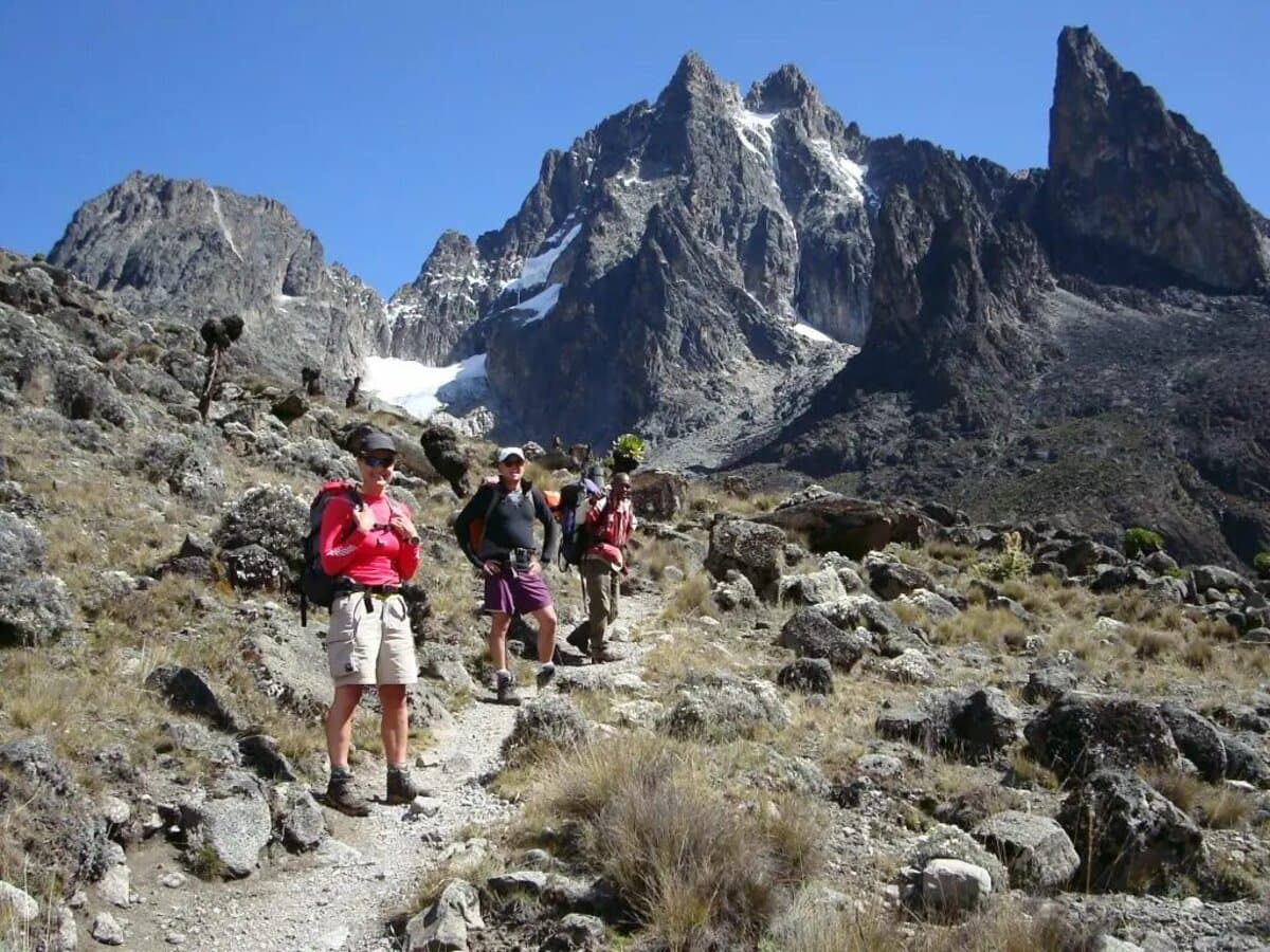 Trekkers hiking towards Mount Kenya's jagged peaks with glaciers